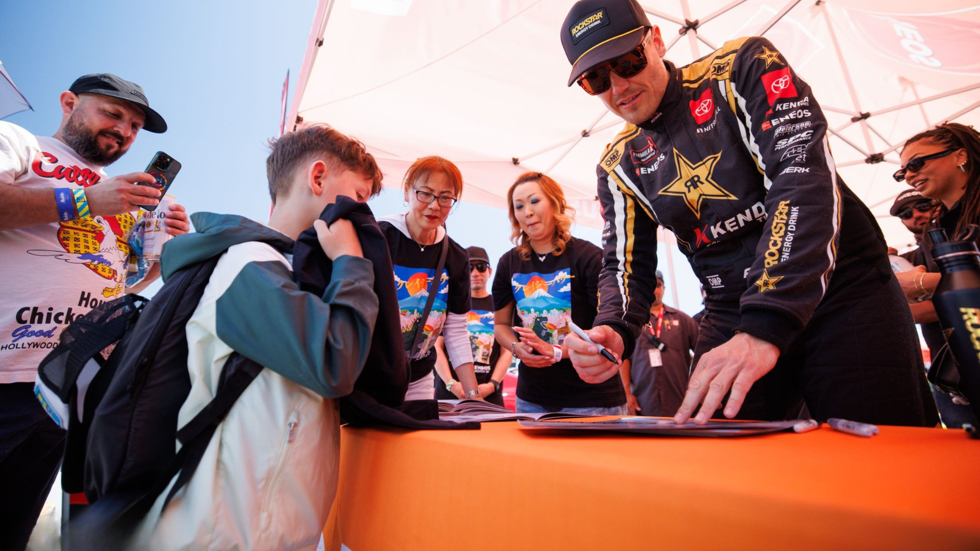 Driver signing merchandise and connecting with fans at the booth