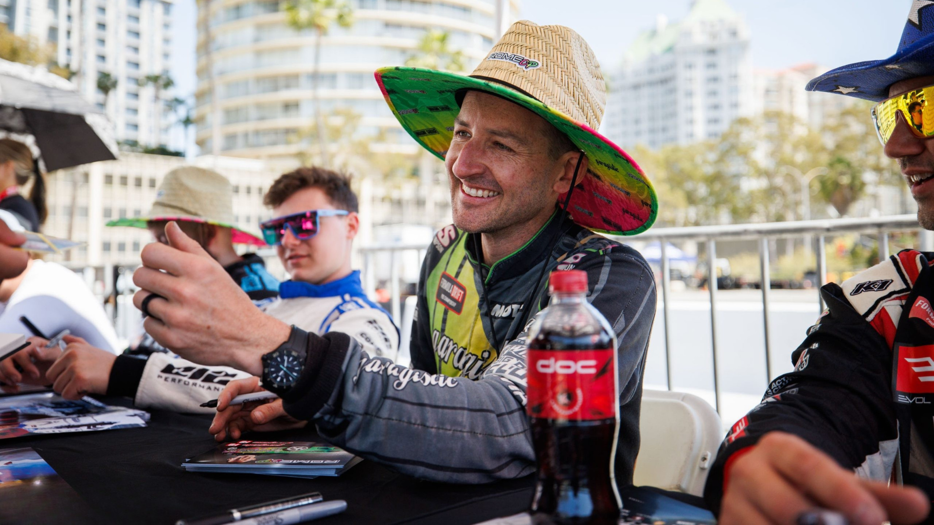 Drivers connecting with fans at a signing table with social content rolling